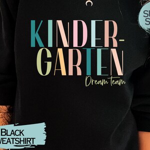 May include: Black sweatshirt with the text "Kindergarten Dream Team" in colorful letters. The text "Super Soft!" is in a circle on the upper right corner of the sweatshirt.