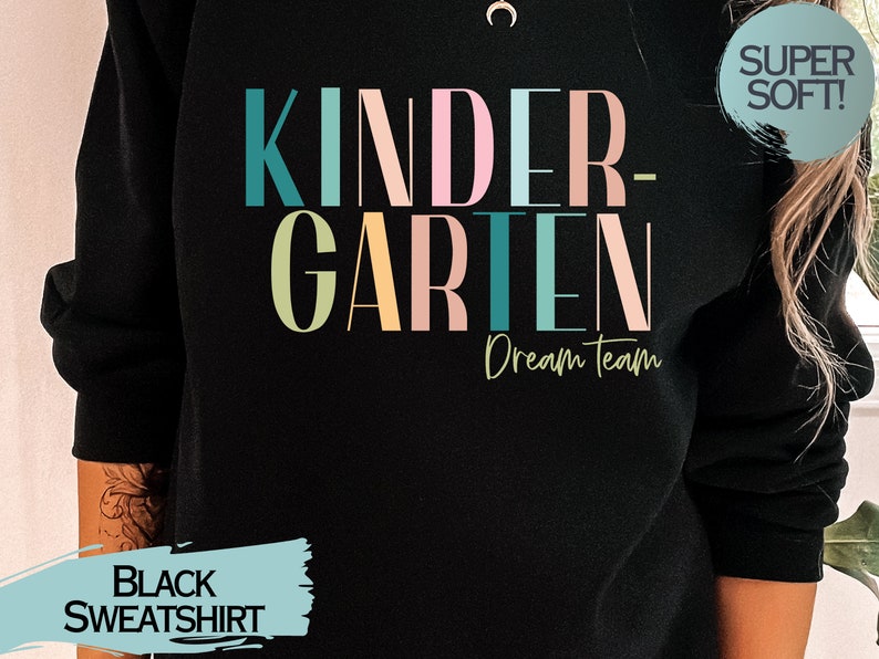 May include: Black sweatshirt with the text "Kindergarten Dream Team" in colorful letters. The text "Super Soft!" is in a circle on the upper right corner of the sweatshirt.