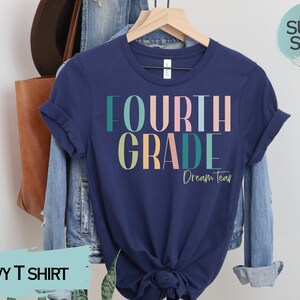May include: Navy blue t-shirt with the text "FOURTH GRADE Dream Team" in colorful letters. The shirt is made of a soft, comfortable material.