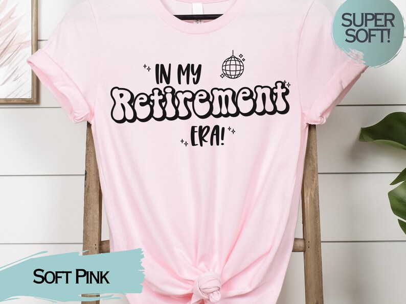 Op de afbeelding: Een zacht roze T-shirt met de tekst "In My Retirement Era!" in zwart, met een discobal-afbeelding boven de tekst.