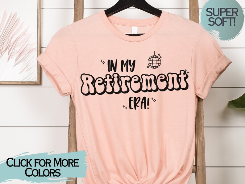 Op de afbeelding: Een roze T-shirt met de tekst "In My Retirement Era!" in zwart, met een discobal-afbeelding. De tekst is in een retro-lettertype.