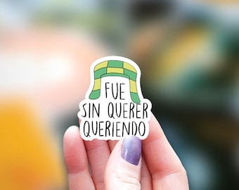May include: A sticker with a green and yellow scarf design and the text "FUE SIN QUERER QUERIENDO".