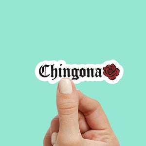 Pu&ograve; includere: Un adesivo con la parola "Chingona" in font gotico e una grafica di rosa rossa.