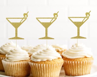 May include: Three gold glitter martini glass cupcake toppers on white frosted cupcakes. The cupcakes are on a white cake stand. The text "Etsy Shop: Cutest Little Topper" is at the bottom of the image.