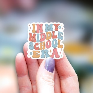 May include: A sticker with the text "In My Middle School Era" in a retro font with colorful letters and stars.
