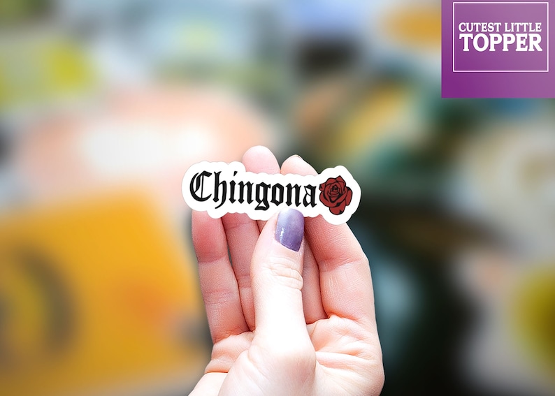 Pu&ograve; includere: Un adesivo bianco con la parola "Chingona" in caratteri gotici neri e una grafica di rosa rossa.