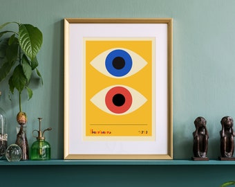 May include: A framed print with a yellow background and two stylised eyes. The top eye is blue with a black pupil, and the bottom eye is red with a black pupil. The print is titled "The Eyes" and is signed "2/3".