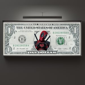 Puede incluir: Un billete de un dólar con un personaje de superhéroe rojo y negro con máscara y espadas. El personaje está haciendo un corazón con sus manos. El billete tiene el texto "THE UNITED STATES OF AMERICA" y "ONE DOLLAR" impreso en él.