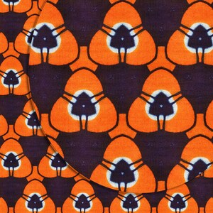 May include: A repeating pattern of orange, white, and black triangular shapes on a dark purple background. The pattern is reminiscent of African fabric.