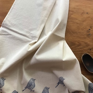 Puede incluir: Una toalla de cocina blanca con un dise&ntilde;o de p&aacute;jaro azul. Los p&aacute;jaros est&aacute;n impresos en un patr&oacute;n repetitivo en toda la toalla.