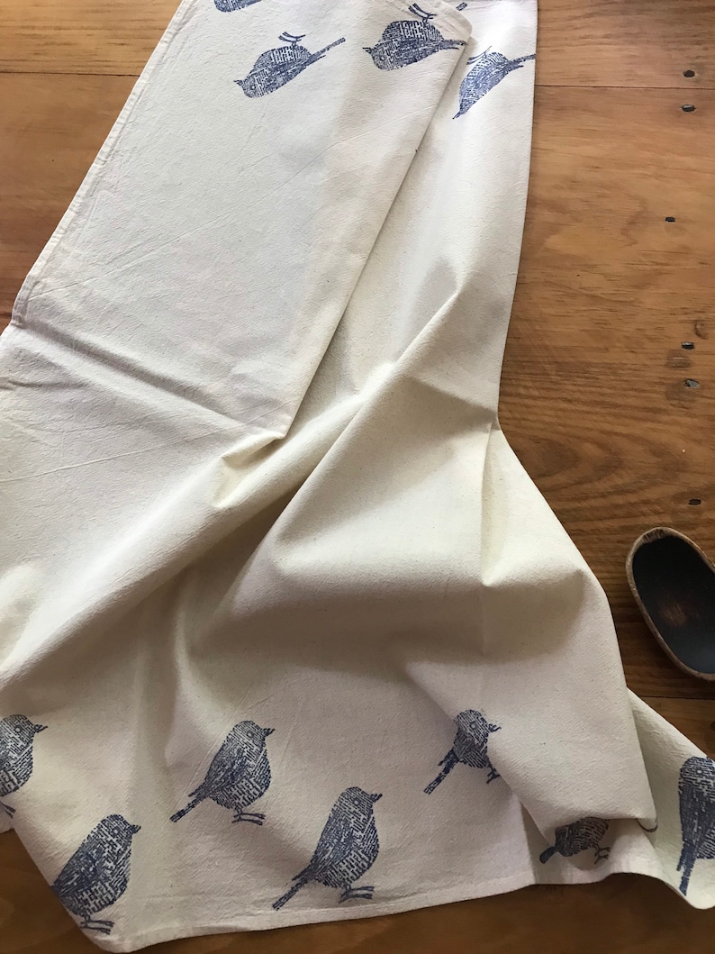 Puede incluir: Una toalla de cocina blanca con un dise&ntilde;o de p&aacute;jaro azul. Los p&aacute;jaros est&aacute;n impresos en un patr&oacute;n repetitivo en toda la toalla.