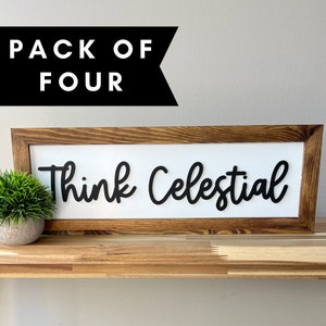 May include: A wooden framed sign with the text "Think Celestial" in black cursive lettering. The sign is on a wooden shelf.