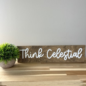 May include: A wooden sign with the text "Think Celestial" in white cursive lettering.
