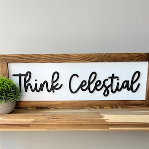 May include: A wooden framed sign with a white background and black lettering that reads "Think Celestial".