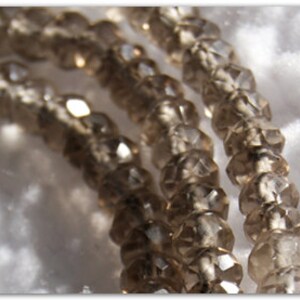 May include: A strand of brown faceted glass beads. The beads are translucent and have a slightly iridescent sheen.