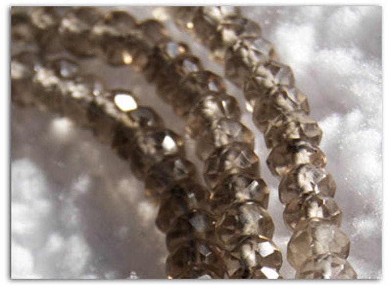May include: A strand of brown faceted glass beads. The beads are translucent and have a slightly iridescent sheen.