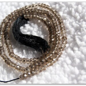 May include: A strand of brown faceted gemstone beads with a black tassel.
