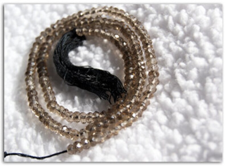 May include: A strand of brown faceted gemstone beads with a black tassel.