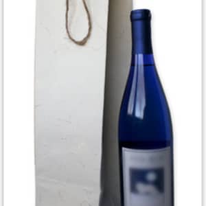 May include: A white paper wine bag with a brown rope handle. The bag is designed to hold a standard-sized wine bottle.