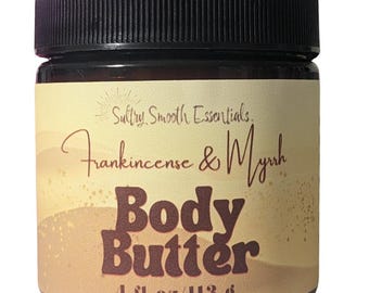 May include: A brown glass jar with a black lid containing body butter. The label is yellow with gold glitter and reads "Sultry Smooth Essentials Frankincense & Myrrh Body Butter 4 fl.oz/113 g".