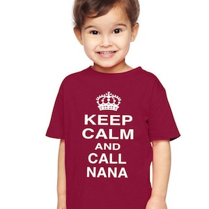 May include: A red toddler t-shirt with white text that reads "Keep Calm and Call Nana" with a crown above the text.