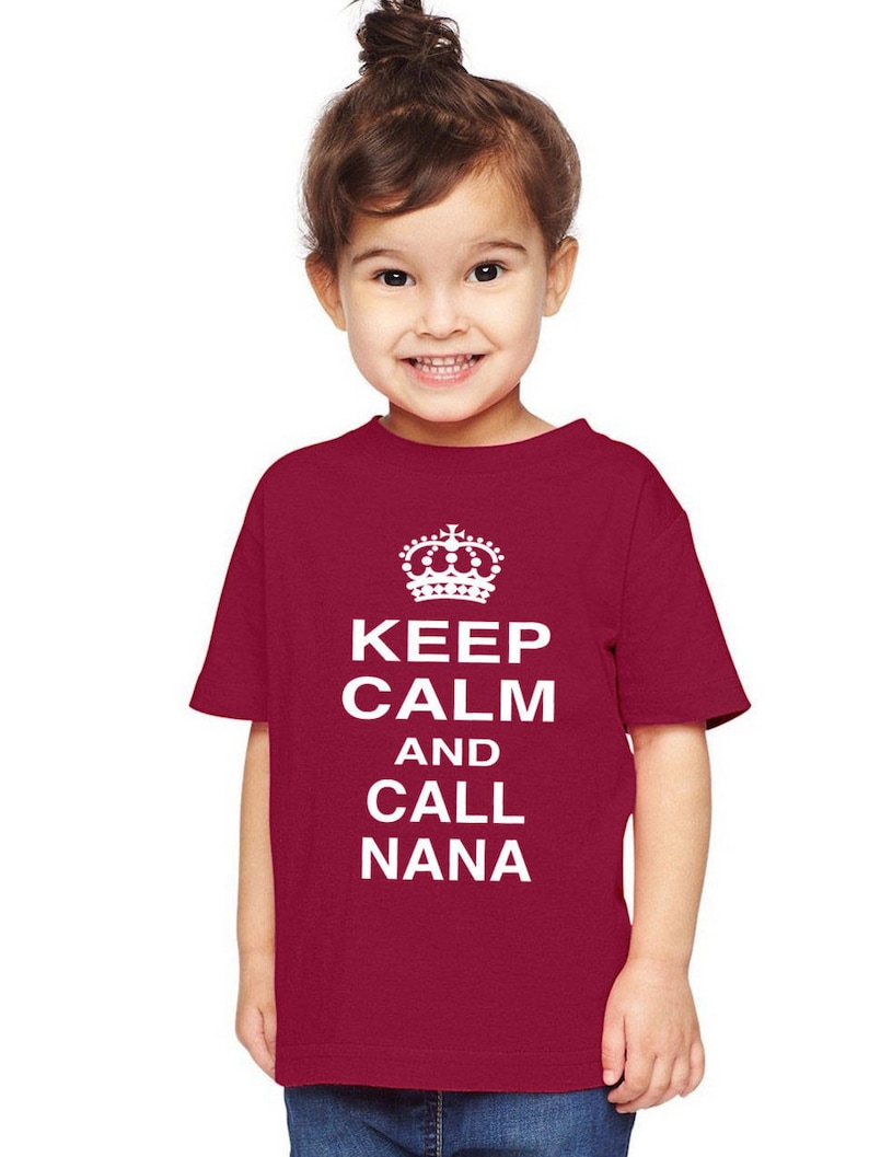 May include: A red toddler t-shirt with white text that reads "Keep Calm and Call Nana" with a crown above the text.