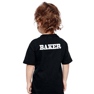 May include: Black t-shirt with white text that says "BAKER" on the back.
