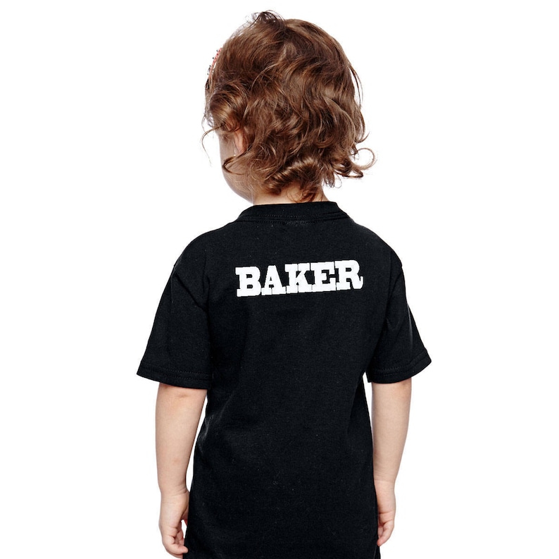 May include: Black t-shirt with white text that says "BAKER" on the back.