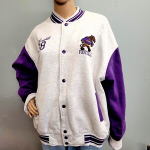 May include: A gray and purple varsity jacket with the word "Cardiff" and the number "8" embroidered on the front. The jacket features a football team logo and the word "FOOTBALL".