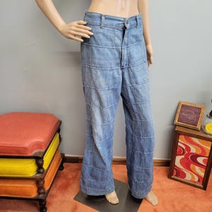 May include: Light blue denim pants with a unique patchwork design. The pants have a high waist and a wide leg, creating a retro style. The denim is a faded blue with visible stitching, giving it a vintage look.