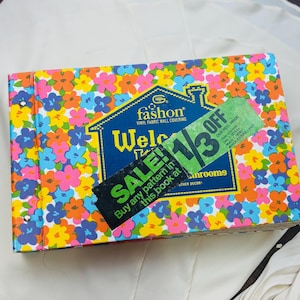 May include: A vintage floral pattern book with a colorful design. The cover features a vibrant mix of orange, pink, and blue flowers. The book has a blue label with the text "fashon" and "Welcome". A green tag indicates a discount.