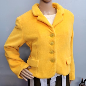 May include: A bright yellow blazer with a classic collar and four matching buttons. The blazer has two front pockets and a soft, textured appearance. The garment is displayed on a mannequin.