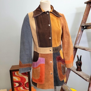 May include: A vintage patchwork suede jacket in a variety of colors, including brown, tan, orange, and blue. The jacket features a collared neckline, button-up front, and two front pockets. The jacket is displayed on a mannequin.