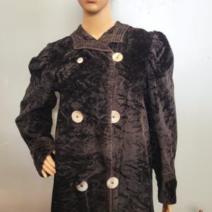 May include: A dark brown velvet coat with large, decorative buttons. The coat features a double-breasted design, a notched collar, and puffed sleeves. The coat's fabric has a textured appearance, and the buttons have a unique, patterned design.