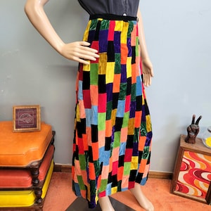 May include: A long skirt featuring a patchwork design of rectangular velvet panels in vibrant colors including red, yellow, blue, green, orange, purple, and black. The skirt has a high waist with a black waistband and a straight, floor-length cut.