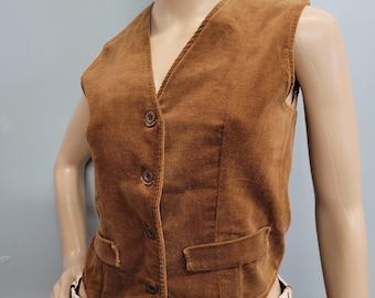 May include: A brown corduroy vest with a V-neck, three buttons, and two front pockets. The vest is sleeveless and has a tailored fit. The fabric has a soft, textured appearance. This vintage vest is a classic piece of apparel.