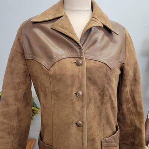 May include: A brown suede jacket with a brown leather yoke and button closure.