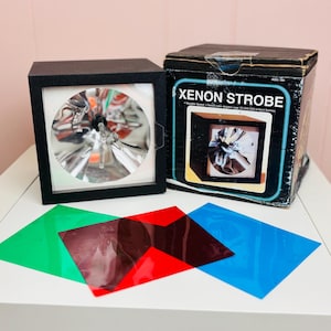 May include: A set of three ceramic mugs with a speckled, matte finish. The mugs are in shades of cream, light gray, and dark gray. Each mug has a simple, minimalist design and a rounded handle.