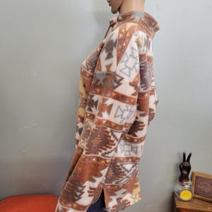 K&ouml;nnte beinhalten: Ein Fleece-Pullover mit einem geometrischen Muster im S&uuml;dwest-Stil in Braun-, Beige-, Creme- und Graut&ouml;nen. Das lang&auml;rmlige Oberteil hat einen Viertel-Rei&szlig;verschluss und eine lockere Passform.