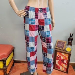 Op de afbeelding: Patchworkbroek in diverse kleuren, waaronder rood, blauw, roze en wit. De broek heeft een mix van ruit-, stippen- en streepmotieven. De broek heeft een knoopsluiting en een elastische tailleband.