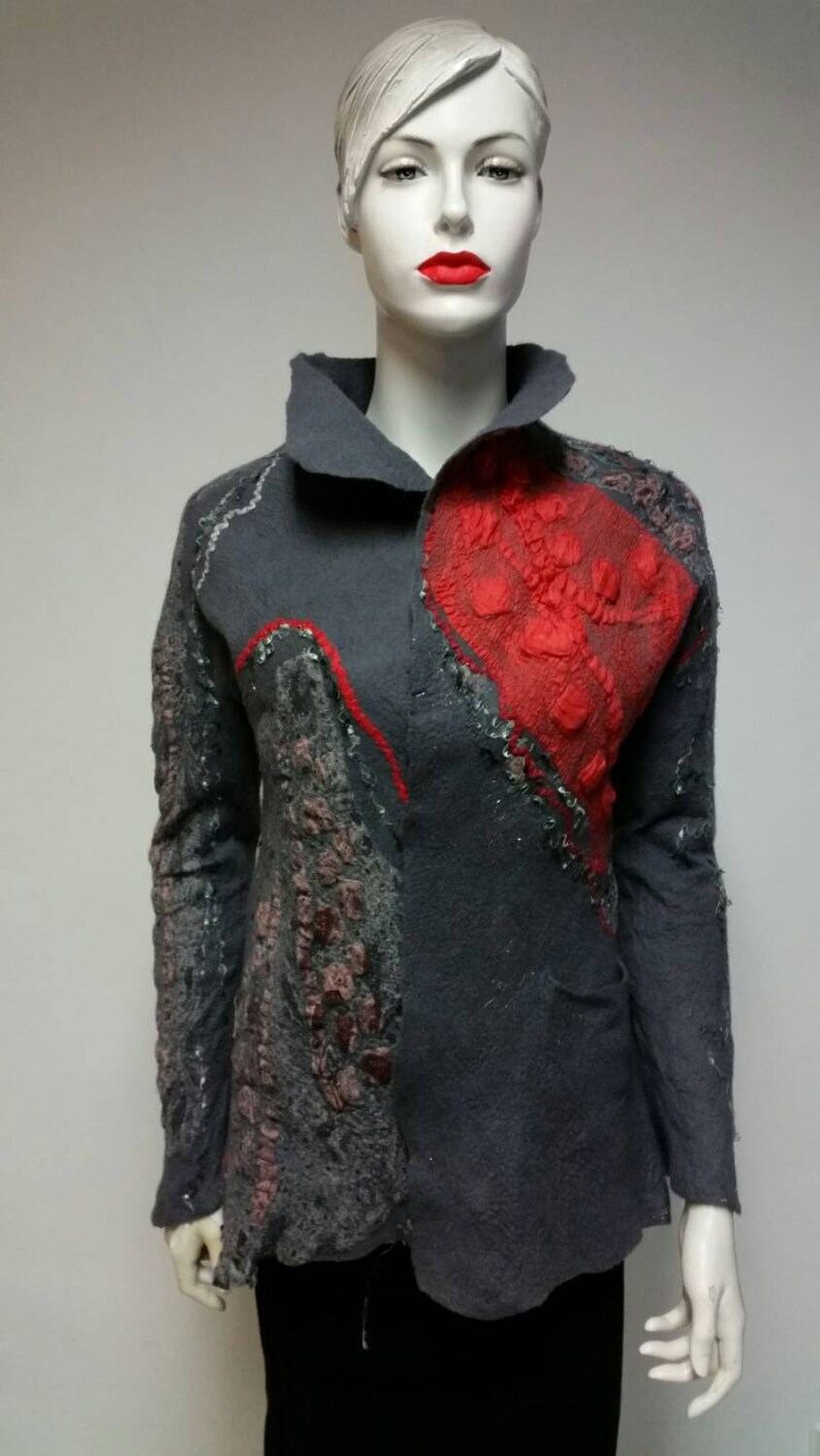 May include: A gray jacket with a red and gray abstract design. The jacket has a collar and long sleeves.