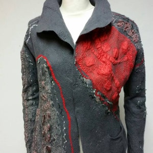 May include: A gray wool jacket with red and gray felt applique details. The jacket has a collar and long sleeves.