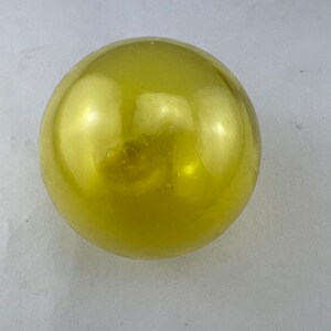May include: A large, round, yellow, glass ball.
