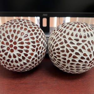 May include: Two white decorative spheres with a brown mosaic pattern. The spheres are made of small, round pieces of tile.