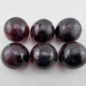 May include: Six smooth, round, dark purple amethyst spheres. The spheres are polished and have a glossy finish.