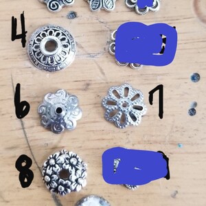 May include: Ten silver metal beads with different designs, numbered 1 through 10. The beads are arranged in a row on a wooden surface.