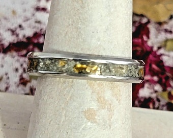 May include: A silver ring with a band of embedded gold flakes and a textured surface.