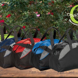 May include: Five different colored duffel bags with black handles and straps. The bags are lined up on a wooden surface. The bags are all the same size and shape. The bags are made of a durable, water-resistant material.  Opastitches Personalized Gifts.