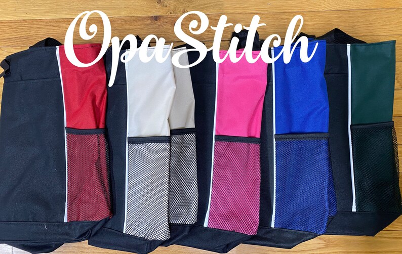 May include: A row of black tote bags with colored side panels and mesh pockets. The side panels are red, beige, gray, pink, blue, and green. Each bag has a white stripe and the text "Opa Stitch" in a cursive font.