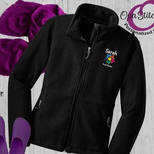 May include: Black fleece jacket with a zipper closure and two pockets. The jacket has a colorful logo embroidered on the left chest that says "Sarah Social Worker".